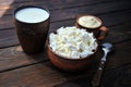 A plate of clay with cottage cheese, a mug of clay with sour cream, a mug with milk and a spoon on a tablen