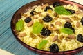 Plate with cooked couscous with almond, raisins, mint and prunes