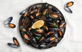 Plate with cooked mussels, parsley and lemon on white tablecloth, flat lay