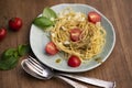 Plate of cooked pasta with cherry tomato slices, cheese, and sweet basil leaves on the table Royalty Free Stock Photo