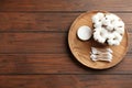 Plate with cotton swabs, pads and flowers on wooden background, top view. Royalty Free Stock Photo