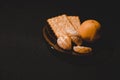 A plate of crackers, manadarines, against a dark background.