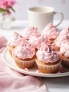 Plate of cupcakes with pink whipped cream frosting.