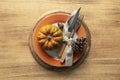 A plate with cutlery is decorated for Thanksgiving with pumpkins and autumn products on a wooden table, Royalty Free Stock Photo