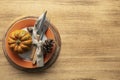 A plate with cutlery is decorated for Thanksgiving with pumpkins and autumn products on a wooden table, Royalty Free Stock Photo