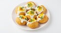 A plate of dahi puri topped with yogurt, sev, cilantro, and mango on a white background surface Royalty Free Stock Photo
