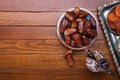 Plate with dates, coffee pot on brown wooden table. Ramadan background. Top view