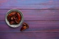 Plate of dates on dark violet wooden background. Flat lay