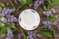 Plate and decor of flowers of lilies of the valley and lilac on the background of vintage wooden boards. Vintage background with Royalty Free Stock Photo