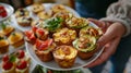 A plate of delectable brunch bites including mini quiches and avocado toast is passed around the table
