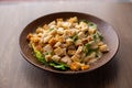 Plate of delicious caesar salad with chicken, grated cheese and crisp crackers on table background closeup. Serving of