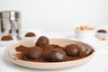 Plate with delicious chocolate truffles and cocoa powder on white table, closeup. Space for text Royalty Free Stock Photo