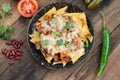 A plate of delicious corn chips nachos in cheddar cheese with beans, tomato, green chili, black olives, cilantro served with guaca Royalty Free Stock Photo