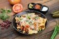 A plate of delicious corn chips nachos in cheddar cheese with beans, tomato, green chili, black olives, cilantro served with guaca Royalty Free Stock Photo