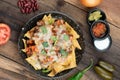 A plate of delicious corn chips nachos in cheddar cheese with beans, tomato, green chili, black olives, cilantro served with guaca Royalty Free Stock Photo