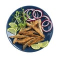 Plate with delicious fried anchovies, lime slices, microgreens and onion rings on white background, top view Royalty Free Stock Photo