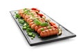 Plate with delicious grilled sausages, chili peppers and herbs on white background Royalty Free Stock Photo