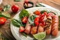 Plate with delicious grilled sausages and vegetables on wooden table, closeup Royalty Free Stock Photo