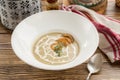 A plate of delicious homemade mushroom cream soup with onion rings on top on wooden table Royalty Free Stock Photo