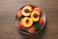 Plate with delicious juicy peaches and leaves on wooden table, top view Royalty Free Stock Photo