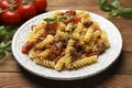 Plate of delicious pasta with minced meat, tomatoes and basil on wooden table, closeup Royalty Free Stock Photo