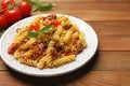 Plate of delicious pasta with minced meat, tomatoes and basil on wooden table, closeup Royalty Free Stock Photo