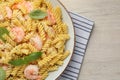 Plate of delicious pasta with shrimps, basil and parmesan cheese on light wooden table, top view. Space for text Royalty Free Stock Photo