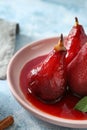 Plate with delicious poached pears in red wine on color table