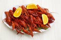 Plate with delicious red boiled crayfish and orange on white wooden table, above view Royalty Free Stock Photo