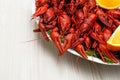 Plate with delicious red boiled crayfish and orange on white wooden table Royalty Free Stock Photo