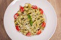 Plate with delicious tagliatelle pasta with pesto sauce, parmesan, cherry tomatoes and basil leafs on white plate. Top down view Royalty Free Stock Photo