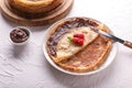 Plate with delicious thin pancakes, raspberries and chocolate paste on light table