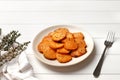 Plate with deliciously cooked sweet potatoes, rosemary, sauce and spices, herbs on a wooden Royalty Free Stock Photo