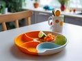 Plate with division for portions and cup for small children on table in kitchen