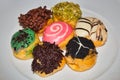 A plate of doughnuts in various flavors and toppings
