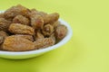 Plate of Dried date fruits or Phoenix dactylifera on a yellowbackground