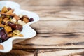 Plate of dried fruits on wooden table, Mix of nuts and berries: cashews, hazelnut, almonds, yellow, brown and blue