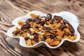 Plate of dried fruits on wooden table, Mix of nuts and berries: raisins, hazelnut, cashews, almonds, yellow, cranberries