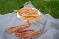 Plate of dry fish pieces on a white plate, with a blanket draped beneath