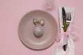 Plate with eating utensils on a napkin and an egg on a pastel pink background Easter menu concept Royalty Free Stock Photo