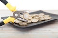 A plate of euro coins and a pair of pliers holding a coin