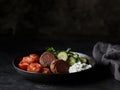 A plate featuring meatballs, cherry tomatoes, cucumber slices, and a yogurt dip Royalty Free Stock Photo