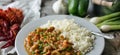 Plate filled with crawfish etouffee and rice. Shown with whole boiled crawfish and green onions in the background.