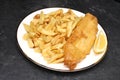 A plate of fish and chips with a slice of lemon from an English fish and chips shop Royalty Free Stock Photo