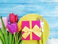 Plate, flower tulip, gift box celebration on a blue wooden background