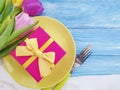 plate, flower tulip, gift box on a blue wooden background