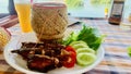 A traditional Laos Rice Basket and plate of other food with a bowl of orange drink in the background Royalty Free Stock Photo