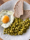 Plate of food, dinner or brunch with egg, peas with herbs and slices of homemade bread. Food ready to eat