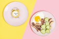 Plate with food and empty plate on pink and yellow background top view, intermittent fasting concept. Royalty Free Stock Photo