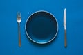 Color plate fork and knife  on blue background. Royalty Free Stock Photo